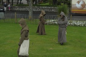 Three figures dressed as monks walking a labyrinth in Largs