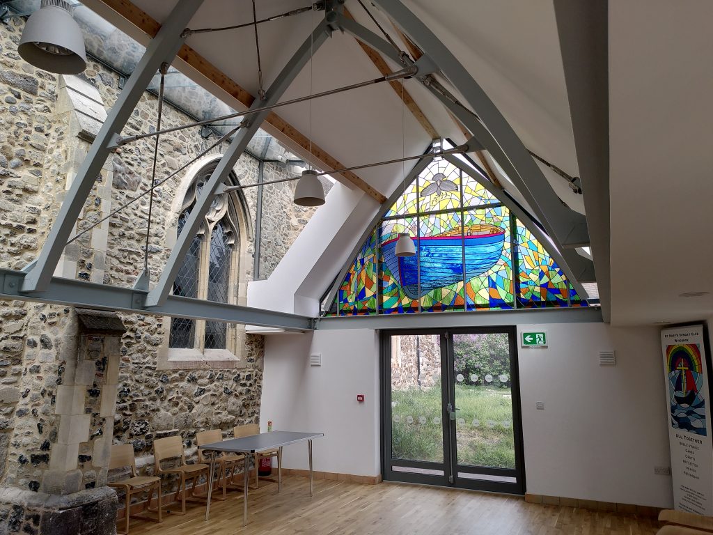 The stained glass window in it's setting. The morern hall complimenting the traditional stone building.